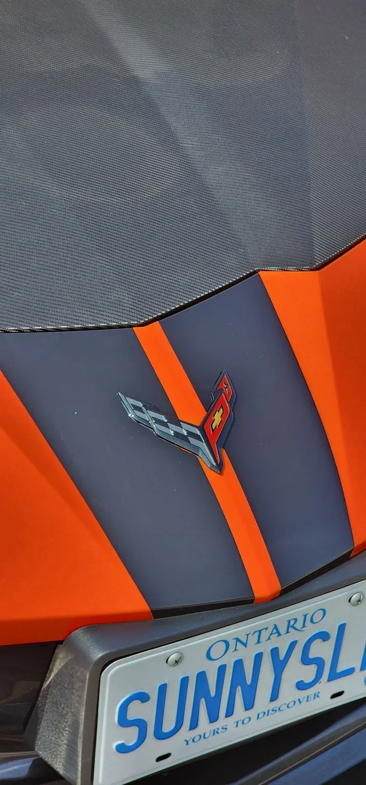 Racing stripes over the rear deck of an orange Corvette C8